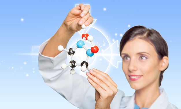 A female scientist in a lab coat examining a molecular model, representing medical research, biotechnology, healthcare innovation, and pharmaceutical advancements.