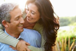 A happy middle-aged couple embracing outdoors, symbolizing healthy aging, wellness, and maintaining an active lifestyle for long-term health.