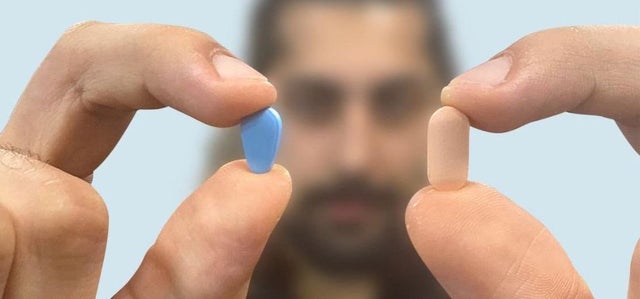 A man holds a blue Viagra (Sildenafil) pill in one hand and a beige Cialis (Tadalafil) pill in the other, highlighting the differences in erectile dysfunction treatments.