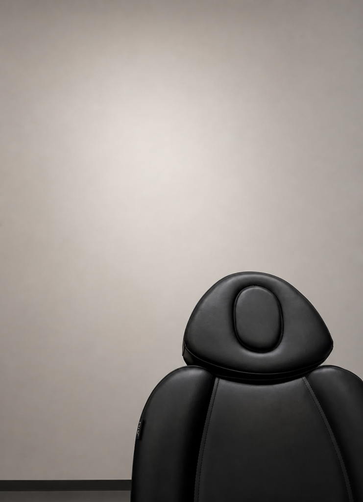 Black leather medical chair against a soft neutral gradient background with subtle lighting, creating a clean and professional clinical setting.