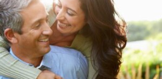 A happy middle-aged couple embracing outdoors, symbolizing healthy aging, wellness, and maintaining an active lifestyle for long-term health.